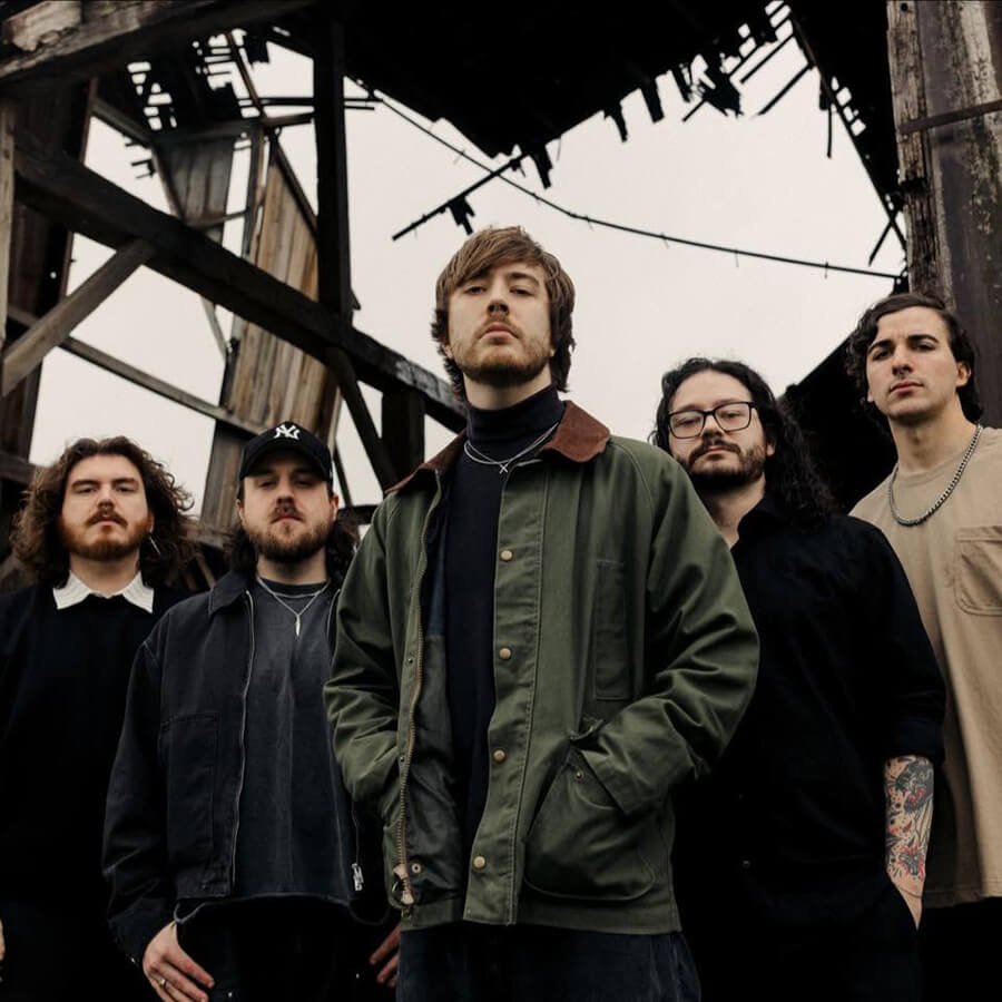 Boundaries band members posing outdoors beneath an industrial structure