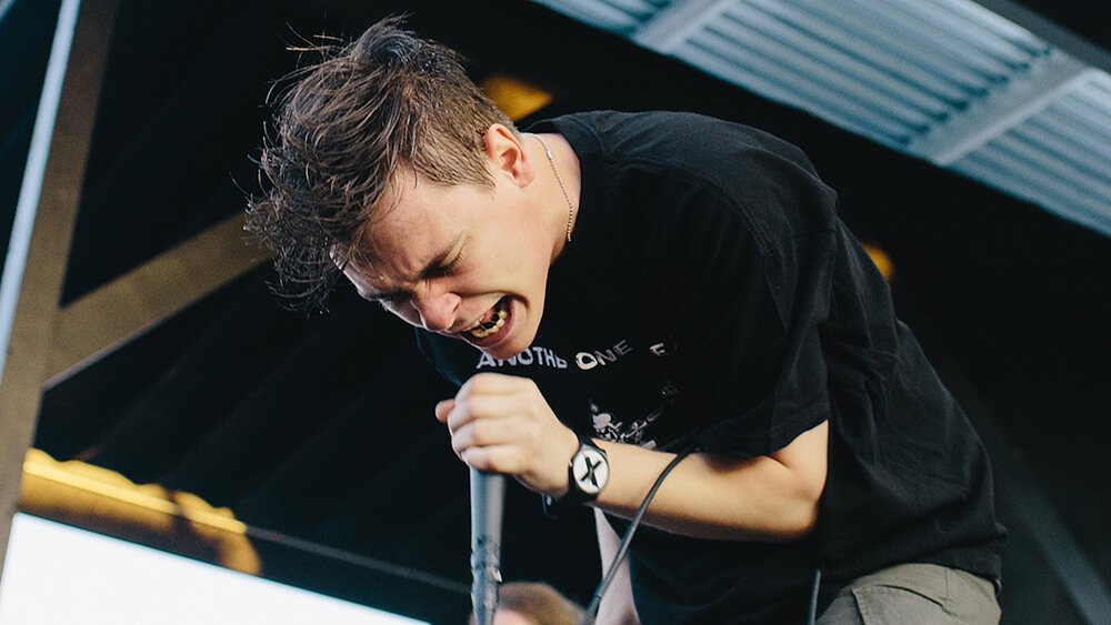Knocked Loose vocalist performing live with a handheld microphone